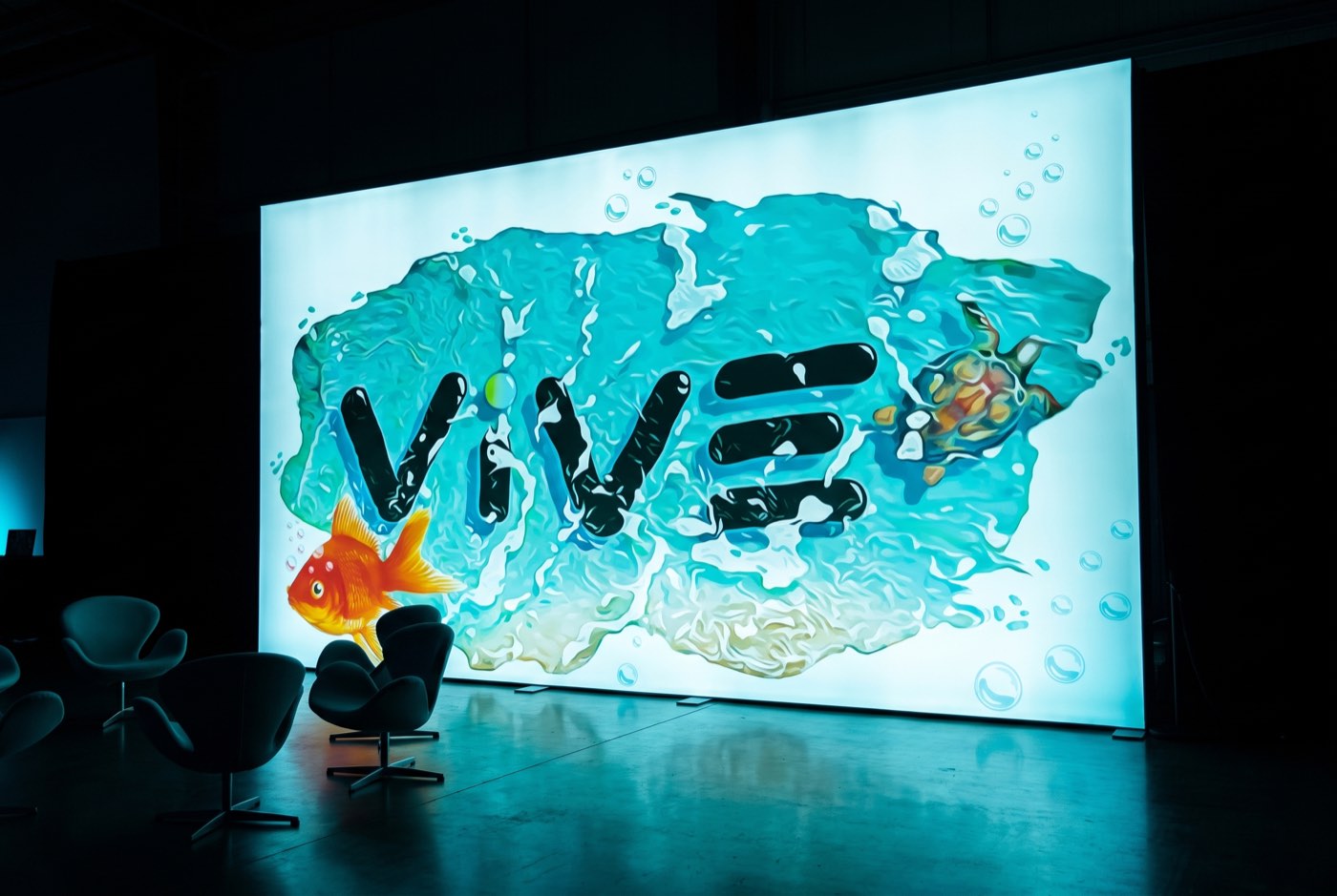 A backlit SEG fabric lightbox produced by Binick for VIVE, glowing in a dark event venue